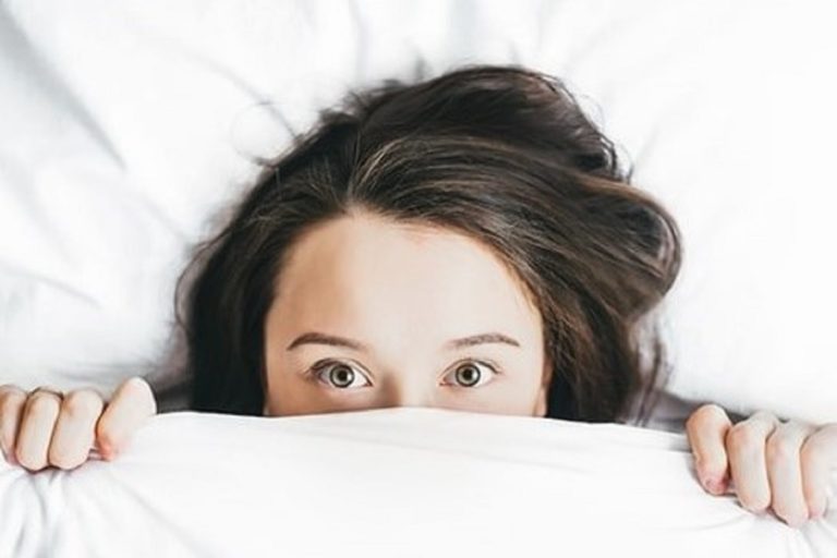Woman peeking out of her bed covers