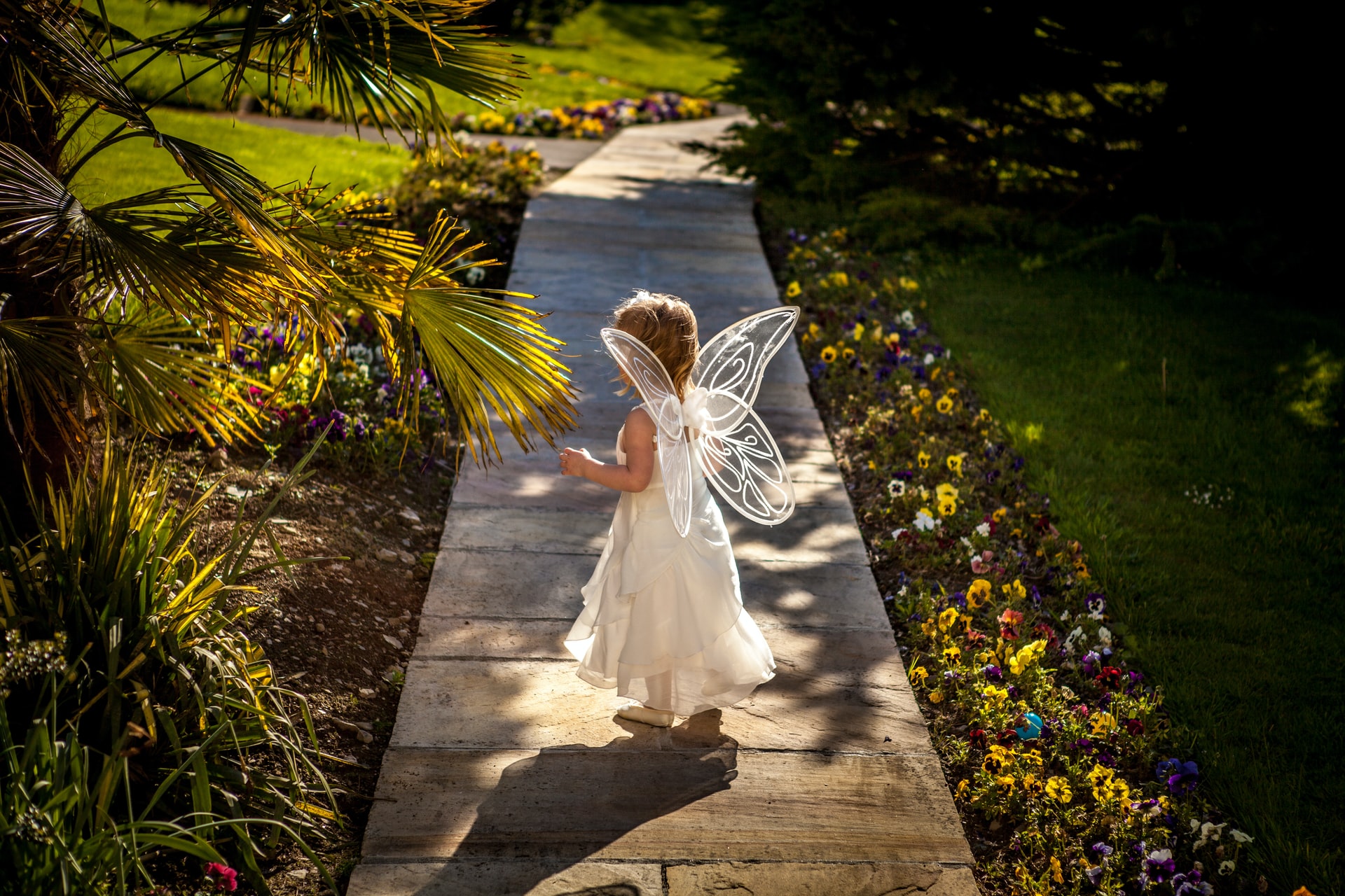 Small child with wings on garden path